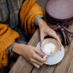 woman-drinking-coffee-stylish-bag-table-wearing-grey-dress-orange-plaid-enjoying-cozy-morning-cafe